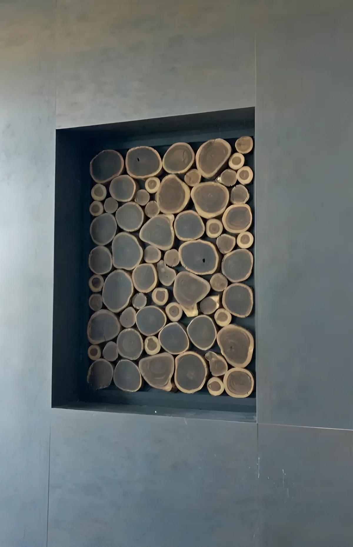 Muro decorativo con rodajas de madera natural sobre fondo antracita